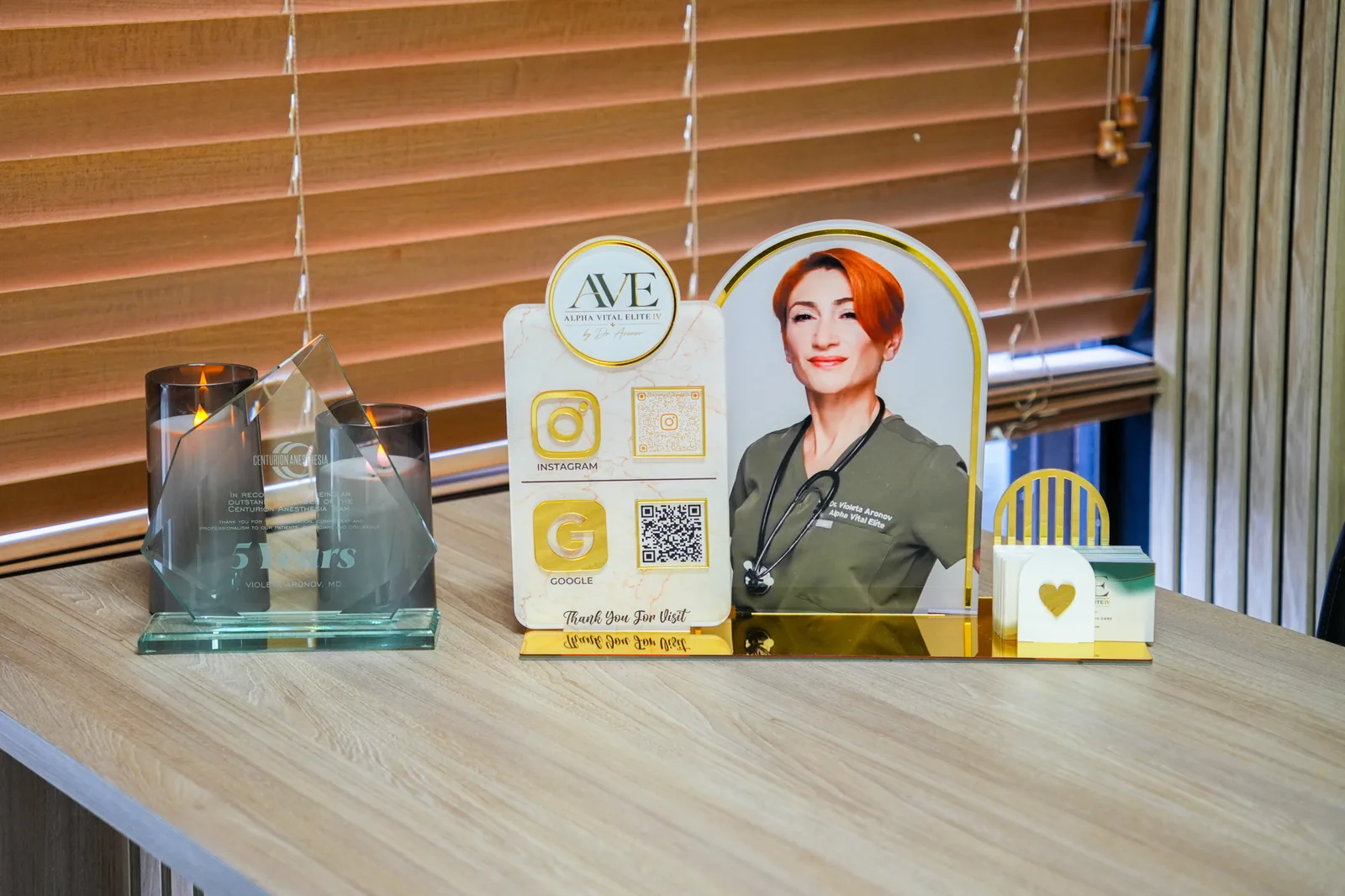 Alpha Vital Elite IV business cards in a gold acrylic holder beside a QR review stand