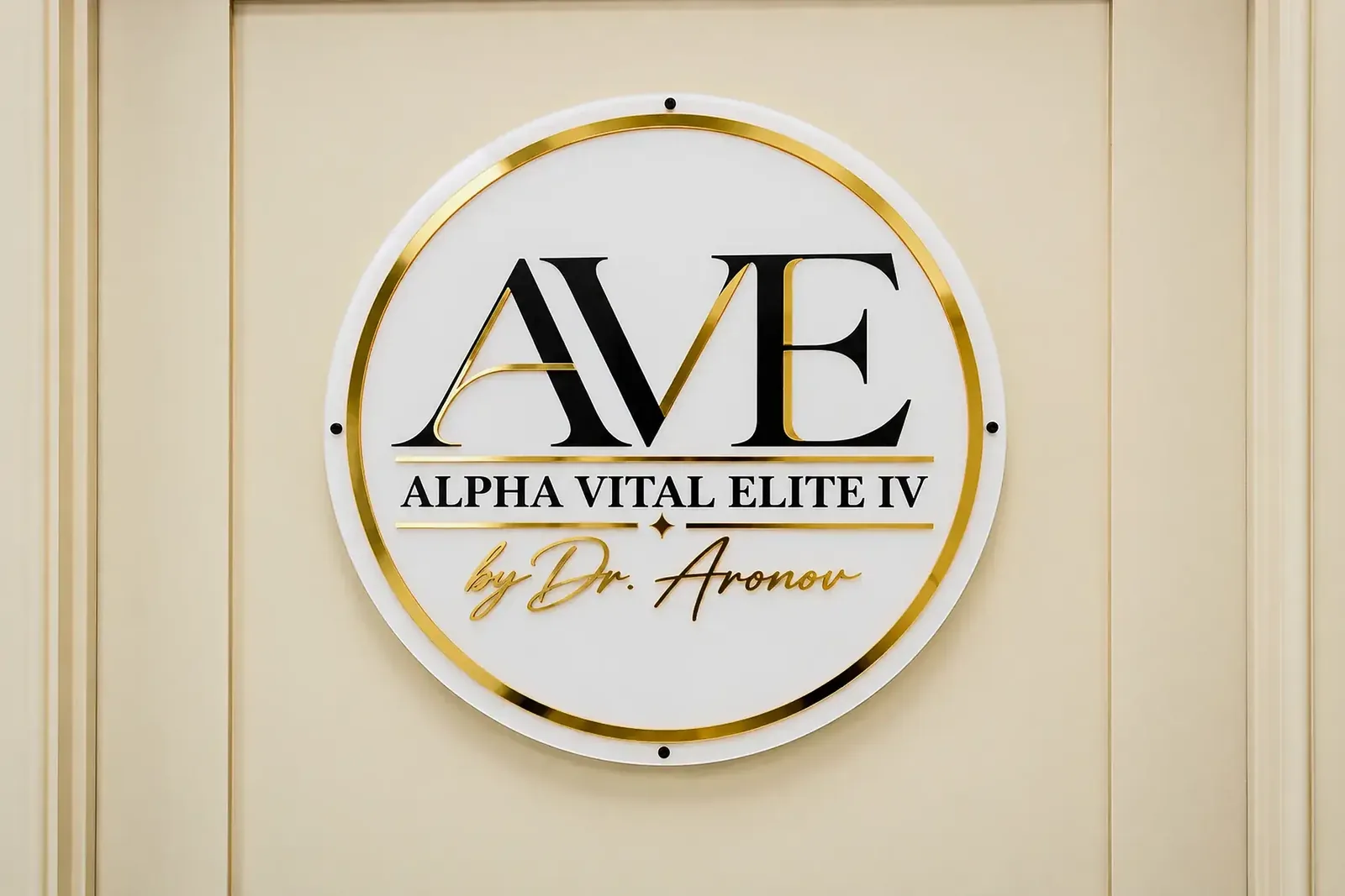 Circle acrylic logo sign with gold ring on the treatment-room door at Alpha Vital Elite IV